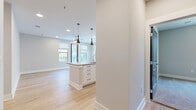 This single-floor residence presents a clean, contemporary design with a neutral color palette and thoughtful layout. The open-concept kitchen serves as the heart of the home, anchored by a substantial center island with an integrated sink, quartz countertops, and ample drawer storage. White shaker-style cabinetry with matte black hardware lines the perimeter walls, complemented by stainless steel appliances including a refrigerator, range, and microwave. Three striking dark pendant lights hang above the island, adding a modern focal point. Light-toned hardwood flooring flows throughout the kitchen and living areas, while large windows invite abundant natural light and offer views of surrounding greenery.

The bedrooms are finished with plush carpet and ceiling fans, each featuring windows with outdoor views that enhance the sense of openness. Multiple walk-in closets provide generous storage with wire shelving systems for organization.

The primary bathroom features a dual-sink vanity with quartz countertops, white cabinetry with black hardware, a large mirror with vanity lighting, and a glass-enclosed shower. A secondary bathroom offers a tiled tub-shower combination, a single-sink vanity, and hardwood-style flooring, completing this well-appointed residence.