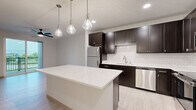 This 1-bedroom, 1-bathroom unit in De Forest, Wisconsin offers a thoughtfully designed layout that maximizes functionality and comfort. The open-concept living and kitchen area serves as the heart of the home, featuring striking dark espresso cabinetry that contrasts beautifully against a crisp white subway tile backsplash and a large white quartz island. Stainless steel appliances, recessed lighting, and elegant pendant lights add a modern, polished feel to the kitchen space. Light-toned luxury vinyl plank flooring runs throughout the main living areas, lending a clean and cohesive aesthetic. The spacious bedroom is finished with plush wall-to-wall carpeting, a ceiling fan, and generous natural light from multiple windows with views to the outdoors. A dedicated closet provides practical storage within the bedroom. The bathroom is well-appointed with light wood-look tile flooring, a dark vanity with ample counter space, and accessibility-friendly grab bars. A dedicated closet is also conveniently located just off the bathroom area. The unit's neutral color palette and modern fixtures create a bright, welcoming ambiance throughout, making it a comfortable and stylish home in the heart of De Forest.