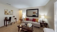 This single-floor residence offers a thoughtfully designed layout that balances comfort and functionality across several well-defined spaces. The living room provides a welcoming atmosphere with soft carpeted flooring, neutral-toned walls, and a large window fitted with blinds that allows natural light to fill the room. A bold framed mirror serves as a striking focal point, enhancing the sense of space and depth.

Adjacent to the living area, the dining space features hardwood-style flooring and a sliding glass door dressed with vertical blinds, offering access to the outdoors. The galley-style kitchen is equipped with dark granite-style countertops, rich wood cabinetry, a double-basin sink, and black appliances, providing ample storage and prep space.

The residence includes multiple bedrooms, each outfitted with plush carpet, ceiling fans with integrated lighting, natural light from window blinds, and generous closet access. The rooms offer a calm, restful ambiance suited for comfortable living.

Two bathrooms serve the residence — one features a tub-shower combination with a patterned yellow curtain and a built-in wood shelving unit, while the second offers a tub-shower combo with a bold navy curtain, dark granite vanity countertop, and a large mirror. Both bathrooms include hardwood-style flooring and classic white fixtures throughout.
