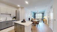 Located at 5441 Greenwich Rd in Virginia Beach, VA, this single-floor, 2-bedroom, 3-bathroom residence offers a thoughtfully designed layout with contemporary finishes and a cohesive aesthetic throughout. The open-concept kitchen and living area serves as the heart of the home, where the kitchen impresses with two-tone gray and white cabinetry, a classic subway tile backsplash, stainless steel appliances, light wood-look flooring, and a central island with seating — ideal for casual dining and entertaining. The living room flows naturally from the kitchen, featuring a ceiling fan, large windows that invite abundant natural light, and views of the surrounding community. Soft, calming accent walls in muted teal tones carry through both the living area and bedrooms, creating a serene atmosphere. The primary bedroom is a comfortable retreat with plush carpet, a walk-in closet, and a private en-suite bathroom featuring gray vanity cabinetry and wood-look flooring. The second bedroom is equally inviting, with its own access to a well-appointed bathroom. A dedicated closet adds practical storage. Throughout the residence, the design balances modern functionality with a warm, welcoming ambiance, making it a refined and comfortable place to call home.