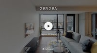 Located in the heart of Minneapolis at 811 Washington Ave S, this contemporary residence offers a thoughtfully designed single-floor layout with a clean, modern aesthetic throughout. The open-concept kitchen is a standout feature, equipped with stainless steel appliances including a gas range, microwave, and French door refrigerator. Rich dark wood cabinetry pairs with a white subway tile backsplash and a central island with a neutral countertop, complemented by stylish pendant and track lighting. Wood-look flooring adds warmth to the kitchen and living areas. The living room enjoys generous natural light through floor-to-ceiling windows, offering views of the surrounding urban landscape and access to a private balcony. The primary bedroom features plush carpeting, a ceiling fan, and expansive windows with a concrete accent column, providing an industrial-chic touch. A walk-in closet leads directly to an en-suite bathroom finished with subway tile, a glass-enclosed shower, and large-format tile flooring. Additional bedrooms are carpeted and well-lit, with one featuring corner windows. A second full bathroom mirrors the refined finishes, with a soaking tub and dark wood vanity. The overall ambiance is contemporary, clean, and urban.