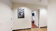 Located at 1120 N Division St in Spokane, WA, this well-appointed one-bedroom, one-bathroom unit offers a thoughtfully designed single-floor layout with generous living space. The open-concept area seamlessly connects the living room, dining room, and kitchen, creating an inviting and functional environment. Large floor-to-ceiling windows flood the living and dining areas with natural light while providing sweeping urban views of the surrounding Spokane cityscape, complemented by sleek roller shades for privacy and light control. Light hardwood flooring runs throughout the main living areas, lending a warm, contemporary feel. The kitchen is outfitted with dark espresso cabinetry, stainless steel appliances including a refrigerator, range, microwave, and dishwasher, and stone-toned countertops. The spacious bedroom features a window with urban views, a bold patterned area rug, and direct access to a dedicated walk-in closet complete with built-in cabinetry and a full-length hanging rod. The bathroom is finished with tile flooring, dark wood vanity cabinetry, a stone countertop, a large mirror, and a tall storage tower. A hallway with its own distinct character connects the rooms, adorned with wall art that adds a modern, creative touch to the interior ambiance.