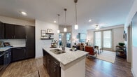 This well-appointed single-floor residence offers a thoughtfully designed open-concept layout that seamlessly connects the kitchen, dining, and living areas. The kitchen serves as a central hub, featuring a large island with granite countertops, a double basin sink, pendant lighting, dark espresso cabinetry, a tile backsplash, and stainless steel appliances. Bar-height seating at the island adds a casual dining option, while recessed lighting ensures the space is well-lit throughout.

The living room is bright and inviting, benefiting from large windows and a sliding glass door that allows generous natural light. A ceiling fan adds comfort, and wood-style flooring runs consistently through the main living areas, creating a cohesive aesthetic.

The two bedrooms are carpeted for comfort and each feature large windows with blinds and curtains, ceiling fans, and ample natural light. One bedroom includes access to a walk-in closet, while the other offers scenic outdoor views.

Both bathrooms are finished with granite-topped dark vanities and wood-style tile flooring. One bathroom includes a tub-shower combination, while the other provides access to a walk-in closet with built-in shelving. The overall design balances modern finishes with a warm, neutral palette throughout.