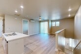 Located at 3100 N Akers St in Visalia, CA, this well-appointed one-bedroom, one-bathroom residence offers a thoughtfully designed layout across a single floor, accessible via a staircase with a clean white handrail and light wood-toned steps. The open-concept living, dining, and kitchen area forms the heart of the home, bathed in natural light from multiple windows and a sliding glass door that leads to a private balcony. Light hardwood flooring flows throughout the main living spaces, complementing the warm, neutral-toned walls. A ceiling fan with integrated lighting adds both comfort and function to the living area, which also features a wall-mounted mini-split system for efficient climate control. The modern kitchen is a standout feature, showcasing crisp white shaker cabinetry, marble-look quartz countertops, a center island with a sink, and a full suite of stainless steel appliances including a refrigerator, range, and over-the-range microwave. Recessed lighting illuminates the space throughout. The spacious primary bedroom includes its own ceiling fan, a wall-mounted mini-split unit, a sliding glass door with vertical blinds, and a closet. A full bathroom, dedicated laundry area, and entrance complete this efficiently designed and move-in ready home.