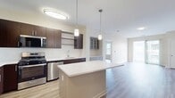 This contemporary 1020 square foot apartment offers a well-designed living space with two bedrooms and two bathrooms. The open-concept layout seamlessly integrates the kitchen, living, and dining areas, creating an expansive feel. The gourmet kitchen boasts dark wood cabinetry, stainless steel appliances, and a large center island with a white quartz countertop, perfect for meal preparation and casual dining.

The primary bedroom, measuring 170 square feet, provides ample space and features large windows that allow natural light to flood the room. Both bathrooms are finished with modern fixtures, including a vanity with wooden cabinetry and a shower-tub combination.

Throughout the apartment, wood-look flooring adds warmth and durability, while the neutral color palette creates a fresh, clean aesthetic. The living area extends to a private balcony, offering outdoor space and views of the surrounding area.

Additional features include a ceiling fan in the bedroom for added comfort, and strategically placed lighting fixtures that enhance the overall ambiance. The apartment's thoughtful design maximizes space efficiency, with built-in closets and storage solutions throughout. This modern dwelling combines style and functionality, making it an ideal home for contemporary urban living.