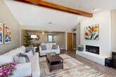 Located at 4020 Versailles Blvd in Oklahoma City, this single-story home offers a thoughtfully designed layout comprising one bedroom, two bathrooms, a dedicated office, and open-concept living and dining areas. The spacious living room immediately draws attention with its vaulted ceiling adorned by rich, exposed wood beams and a striking white-painted brick fireplace that serves as a dramatic focal point. Wood-look flooring flows throughout the main living areas, complementing the warm architectural details. Natural light filters in through multiple windows, enhancing the bright and airy atmosphere. The kitchen features warm wood cabinetry, black appliances, and a peninsula that connects seamlessly to both the dining and living areas, making it ideal for entertaining. The adjacent dining room is defined by crown molding, a ceiling fan, and a pass-through window to the kitchen. The generously sized primary bedroom is carpeted and includes crown molding, a ceiling fan, and windows that invite natural light. The dedicated office, also carpeted with crown molding and natural light, provides a quiet, functional workspace. Two bathrooms serve the home, one featuring a sliding glass enclosed shower. This home offers a comfortable and versatile layout suited for a variety of lifestyles.