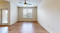 Located at 21 Gramercy Park Dr in Bryan, TX, this one-bedroom, one-bathroom unit offers a well-designed single-floor layout that maximizes its comfortable footprint. The open-concept living area flows naturally into the kitchen, which features a peninsula with granite-style countertops, rich dark wood cabinetry, stainless steel appliances including a refrigerator, electric range, and built-in microwave, all set above warm wood-look flooring. The living area is accented with built-in shelving and track lighting, with a glass door providing access to the exterior. The generously sized bedroom is carpeted for comfort, benefits from multiple windows that invite abundant natural light, and includes a ceiling fan. A spacious walk-in closet with wire shelving provides ample storage. The full bathroom is equipped with a tub-shower combo, a curved curtain rod, and dark wood cabinetry overhead, complemented by wood-look flooring. Neutral warm tones throughout the unit create a cohesive and inviting atmosphere, making this a practical and comfortable living space.