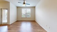 Located at 21 Gramercy Park Dr in Bryan, TX, this one-bedroom, one-bathroom unit offers a well-designed single-floor layout that maximizes its comfortable footprint. The open-concept living area flows naturally into the kitchen, which features a peninsula with granite-style countertops, rich dark wood cabinetry, stainless steel appliances including a refrigerator, electric range, and built-in microwave, all set above warm wood-look flooring. The living area is accented with built-in shelving and track lighting, with a glass door providing access to the exterior. The generously sized bedroom is carpeted for comfort, benefits from multiple windows that invite abundant natural light, and includes a ceiling fan. A spacious walk-in closet with wire shelving provides ample storage. The full bathroom is equipped with a tub-shower combo, a curved curtain rod, and dark wood cabinetry overhead, complemented by wood-look flooring. Neutral warm tones throughout the unit create a cohesive and inviting atmosphere, making this a practical and comfortable living space.
