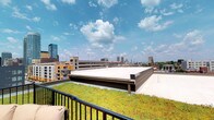 E'laan presents a striking rooftop experience defined by its expansive green roof and open-air terrace. The rooftop level is one of the property's most distinctive features, showcasing a living green roof planted with low-growing, drought-tolerant sedum vegetation that adds a layer of natural beauty and environmental sustainability to the structure. A railed terrace adjoins the green roof area, providing an outdoor vantage point with sweeping, unobstructed panoramic views of the surrounding cityscape. From this elevated position, the urban skyline stretches across the horizon, with a mix of high-rise towers, mid-rise buildings, and architectural landmarks visible in multiple directions, all set beneath open skies. The terrace is designed to serve as a functional outdoor amenity space, offering seating and an open atmosphere ideal for taking in the city views. The combination of the living green roof and the rooftop terrace reflects a thoughtful integration of green design principles with urban living, creating an environment that balances natural elements with a dynamic metropolitan backdrop. The overall ambiance of the rooftop is one of openness and elevation, offering a calm retreat above the energy of the city below.