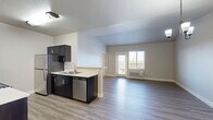 Located at 5715 Red Leaf Dr S in Salem, Oregon, this well-appointed 3-bedroom, 3-bathroom unit offers a thoughtfully designed single-level layout. The open living area features light-toned luxury vinyl plank flooring, vaulted ceilings, and a sliding door that leads to a private balcony with outdoor views, allowing natural light to fill the space. A chandelier adds a refined touch overhead, complementing the clean, neutral color palette throughout.

The galley-style kitchen is a standout feature, showcasing rich dark cabinetry with brushed nickel hardware, white quartz countertops, and a full suite of stainless steel appliances including a range, microwave, and refrigerator. A well-lit hallway connects the kitchen to the three bedrooms, all of which are carpeted for comfort and include closet storage.

The primary bedroom offers a generous footprint with a ceiling fan and direct access to a private en-suite bathroom. Each bathroom is finished with dark vanity cabinetry, white quartz countertops, large mirrors, and wood-look LVP flooring. Accessibility features such as grab bars are present in select bathrooms. The hallway provides additional organization with dark cabinetry storage. This unit combines functional design with modern finishes throughout.