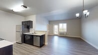 Located at 5715 Red Leaf Dr S in Salem, Oregon, this well-appointed 3-bedroom, 3-bathroom unit offers a thoughtfully designed single-level layout. The open living area features light-toned luxury vinyl plank flooring, vaulted ceilings, and a sliding door that leads to a private balcony with outdoor views, allowing natural light to fill the space. A chandelier adds a refined touch overhead, complementing the clean, neutral color palette throughout.

The galley-style kitchen is a standout feature, showcasing rich dark cabinetry with brushed nickel hardware, white quartz countertops, and a full suite of stainless steel appliances including a range, microwave, and refrigerator. A well-lit hallway connects the kitchen to the three bedrooms, all of which are carpeted for comfort and include closet storage.

The primary bedroom offers a generous footprint with a ceiling fan and direct access to a private en-suite bathroom. Each bathroom is finished with dark vanity cabinetry, white quartz countertops, large mirrors, and wood-look LVP flooring. Accessibility features such as grab bars are present in select bathrooms. The hallway provides additional organization with dark cabinetry storage. This unit combines functional design with modern finishes throughout.