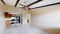 Located at 910 S Volusia Ave in Orange City, Florida, this single-story, one-bedroom, one-bathroom home offers an efficient and functional layout across its single floor. The open-concept main living area seamlessly combines the living room, dining area, and kitchen, creating a cohesive and practical space. A standout architectural feature is the exposed dark wood ceiling beams in the living area, which add character and visual interest. A ceiling fan complements the beams and aids in air circulation. Light-toned ceramic tile flooring runs consistently throughout the home, providing a clean and easy-to-maintain surface.

The kitchen is well-equipped with warm wood cabinetry, a built-in breakfast bar with countertop seating, a gas range, a full-size refrigerator, and a skylight that introduces natural light from above. The bedroom is a comfortable, well-proportioned room with a large window that allows natural light and views of the outdoors, along with two closets providing ample storage. The bathroom is straightforward and functional, featuring tile flooring, a vanity with sink, toilet, and a tiled shower. Neutral, warm beige tones are used throughout, creating a calm and cohesive atmosphere across the entire home.