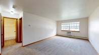 Located at 4300 S 60th St in Greenfield, WI, this one-bedroom, one-bathroom unit offers a well-organized single-floor layout designed for comfortable everyday living. The expansive living room is finished with plush wall-to-wall carpeting, warm wood baseboards, and a large multi-pane window that fills the space with natural light. A wall-mounted HVAC unit and baseboard heating system ensure year-round climate comfort. The galley-style kitchen is efficiently designed with warm wood cabinetry, granite-look countertops, a stainless steel sink, and includes a full-size refrigerator and electric range. Adjacent to the kitchen, the dining area provides a natural flow for everyday meals and entertaining. The generously sized bedroom features soft carpeting, a wide window with a view, baseboard heating, and a large sliding wood-paneled closet that offers ample storage. With four closets total throughout the unit, storage is plentiful. The full bathroom is appointed with a wood vanity, granite-look countertop, a tiled tub-shower combination, and durable wood-look plank flooring, delivering a clean and functional finish. Neutral tones and consistent wood trim details create a cohesive aesthetic throughout the space.