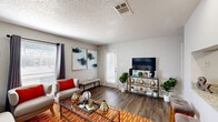 This one-bedroom, one-bathroom residence in Bedford, Texas offers a thoughtfully designed single-story layout that maximizes every square foot. The open-concept living and kitchen area forms the heart of the home, where rich wood-look flooring flows throughout. The living room features neutral gray walls with a bold accent wall, multiple windows that invite natural light, and a private exterior door. A pass-through window connects the living area to the kitchen, creating a seamless social atmosphere ideal for entertaining.

The galley-style kitchen is well-equipped with white cabinetry, granite-look countertops, a subway tile backsplash, stainless steel appliances including a refrigerator, electric range, microwave, and dishwasher, and durable wood-look flooring. A breakfast bar with seating overlooks the living area.

The bedroom offers a cozy retreat with plush carpeting, a window with natural light, and access to a dedicated closet for ample storage. The bathroom features a white vanity with granite-look countertops, a large framed mirror, and wood-look flooring. A tiled tub-shower completes the space. The textured ceilings are consistent throughout, adding a classic finishing touch to this well-designed residence.