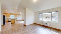 Located on 21st St SE in Menomonie, WI, this single-floor, 4-bedroom, 2-bathroom home offers a well-designed layout with consistent light wood laminate flooring and neutral white walls throughout, creating a bright and cohesive atmosphere. The open-concept living and kitchen area serves as the heart of the home, with vaulted ceilings adding a sense of openness and volume. The kitchen is well-appointed with light maple cabinetry, a central island, stainless steel appliances including a refrigerator, microwave, and range, and ample counter space. A large window over the sink brings in natural light, while recessed lighting ensures the space stays bright. The living area flows seamlessly from the kitchen and features a large window offering views of the surrounding neighborhood. The four bedrooms are comfortable and well-lit, with several rooms featuring ceiling fans and windows that let in abundant natural light. The primary bedroom benefits from vaulted ceilings, enhancing its spacious feel. Both bathrooms are finished with light maple vanities and include a tub/shower combo. A dedicated laundry room houses a stacked washer and dryer unit, adding everyday convenience. The hallway connects all rooms efficiently, rounding out this functional and move-in-ready home.