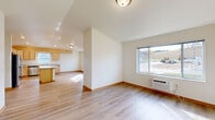 Located on 21st St SE in Menomonie, WI, this single-floor, 4-bedroom, 2-bathroom home offers a well-designed layout with consistent light wood laminate flooring and neutral white walls throughout, creating a bright and cohesive atmosphere. The open-concept living and kitchen area serves as the heart of the home, with vaulted ceilings adding a sense of openness and volume. The kitchen is well-appointed with light maple cabinetry, a central island, stainless steel appliances including a refrigerator, microwave, and range, and ample counter space. A large window over the sink brings in natural light, while recessed lighting ensures the space stays bright. The living area flows seamlessly from the kitchen and features a large window offering views of the surrounding neighborhood. The four bedrooms are comfortable and well-lit, with several rooms featuring ceiling fans and windows that let in abundant natural light. The primary bedroom benefits from vaulted ceilings, enhancing its spacious feel. Both bathrooms are finished with light maple vanities and include a tub/shower combo. A dedicated laundry room houses a stacked washer and dryer unit, adding everyday convenience. The hallway connects all rooms efficiently, rounding out this functional and move-in-ready home.