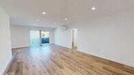 Located in the vibrant East Hollywood neighborhood of Los Angeles, this thoughtfully updated 2-bedroom, 3-bathroom residence offers a clean, modern aesthetic throughout its single-floor layout. Warm-toned hardwood-style flooring flows seamlessly across every room, complemented by crisp white walls and bright recessed lighting that create an open, airy atmosphere.

The spacious living room is a standout feature, offering generous proportions, recessed lighting, a wall-mounted mini-split system for climate control, and sliding glass doors that open onto a private balcony. Adjacent to the living area, the dining space connects naturally to a galley-style kitchen outfitted with white shaker cabinetry, quartz countertops, a classic subway tile backsplash, and a full suite of stainless steel and black appliances including a gas range, microwave, dishwasher, and refrigerator.

Both bedrooms are well-sized and filled with natural light from large windows with blinds. Each room includes a closet with sliding mirrored doors and its own mini-split climate system. All three bathrooms are elegantly finished with large hexagonal tile flooring, white subway tile surrounds, and matte black hardware accents — one featuring a glass-enclosed walk-in shower, and another with a full soaking tub and vanity.