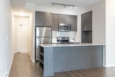 Located at 2550 Eglinton Ave W in Mississauga, Ontario, this well-appointed one-bedroom, one-bathroom unit offers a thoughtfully designed layout that maximizes every square foot. The space is finished with warm hardwood-style flooring throughout, clean white walls, and a neutral palette that creates a bright, cohesive feel from room to room.

The open-concept kitchen and living area forms the heart of the unit. The kitchen is equipped with stainless steel appliances, dark upper cabinetry, a white quartz-topped island with an integrated sink, and a subway tile backsplash — combining style with functionality. Track lighting overhead highlights the modern finishes. The living area flows naturally from the kitchen and opens to floor-to-ceiling sliding glass doors leading to a balcony, offering sweeping elevated views of the Mississauga cityscape and surrounding neighbourhoods.

The bedroom is a calm, private retreat featuring large windows that flood the room with natural light and frame the same impressive city views. A dedicated closet provides practical storage. The bathroom features large-format tile flooring, a modern navy blue vanity with an integrated sink, a framed mirror, and a combined tub and shower. A clean entry corridor with a built-in closet completes the layout, adding additional storage and a welcoming transition into the home.