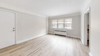 This thoughtfully laid-out one-bedroom, one-bathroom unit at 126 St Paul Ave in Brantford, Ontario offers a clean, neutral aesthetic throughout. Light hardwood-style flooring runs continuously across all rooms, creating a cohesive and bright atmosphere. The living room is a comfortable, open area anchored by a large multi-pane window that floods the space with natural light, complemented by a classic radiator beneath the sill. Soft, warm-toned walls and crisp white trim define the space's simple, understated character. The kitchen is efficiently designed in a galley-style layout, featuring white cabinetry with silver hardware, granite-look countertops, a white tile backsplash, and stainless steel appliances including a range, over-the-range microwave, and refrigerator. A window above the sink brings in additional natural light. The bedroom offers a quiet retreat with a closet and direct access to the hallway, maintaining the same light flooring and neutral palette found throughout the unit. The bathroom is finished with clean white tile surrounding a full soaker tub with an overhead shower. A hallway connects the main areas, providing a practical flow through the unit. The overall ambiance is bright, clean, and move-in ready.