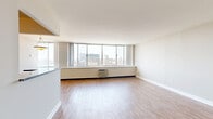 This thoughtfully laid-out 1-bedroom, 1-bathroom residence offers a comfortable and functional living experience across a single floor. The open-plan living and dining area is the standout feature of the home, anchored by an expansive wall of floor-to-ceiling sliding windows that flood the space with natural light and frame breathtaking elevated views of the city skyline and what appears to be a nearby waterway. Wood-style laminate flooring runs throughout the living areas and bedroom, providing a warm and cohesive aesthetic against the clean white walls and trim.

The galley-style kitchen is efficiently designed with warm wood cabinetry, dark granite countertops, white tile flooring, and a full suite of stainless steel appliances including a refrigerator, electric range, microwave, and dishwasher. The spacious bedroom continues the city view theme with its own large windows and includes a sliding-door closet with built-in shelving, alongside a convenient in-unit washer. The bathroom features tile flooring, a granite-topped vanity with warm wood cabinetry, a mirrored medicine cabinet, and a shower/tub combination. A connecting hallway ties the layout together, offering a practical and well-organized flow throughout the residence.