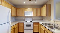 Located at 130 Cumberland Way in Pataskala, Ohio, this single-floor property offers a comfortable and functional living environment. The kitchen is a standout feature, showcasing warm honey-toned oak cabinetry that extends from floor to ceiling, providing generous storage space throughout. Light countertops complement the cabinetry, creating a clean and cohesive aesthetic. White appliances, including a coil-burner range, over-the-range microwave, and a sink, are neatly integrated into the layout, which follows a practical U-shaped configuration that maximizes workspace efficiency. Track lighting mounted on the ceiling ensures the kitchen is well-lit, enhancing both functionality and visibility. The textured ceiling adds a classic residential character to the space. The overall design reflects a straightforward, practical approach to single-floor living, making it well-suited for everyday use. With its neutral color palette and traditional style, this Pataskala property offers a welcoming atmosphere that serves as a solid foundation for comfortable living.