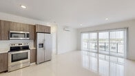 Located at 25850 SW 140th Ct, Unit 507 in Homestead, FL, this modern one-bedroom, one-bathroom unit offers a thoughtfully designed open-concept layout. Large-format glossy tile flooring runs throughout the entire space, enhancing the bright, clean aesthetic. The combined kitchen and living area is the heart of the unit, featuring contemporary wood-toned cabinetry, light countertops, a stainless steel sink with a pull-down faucet, a dishwasher, a stainless steel range with microwave above, and a full-size French door refrigerator. Recessed lighting and a wall-mounted mini-split air conditioning system ensure comfort year-round. Floor-to-ceiling sliding glass doors with vertical blinds lead to a private balcony, flooding the living area with natural light and providing open views of the surrounding neighborhood. The bedroom is a serene, airy retreat with its own sliding glass door access to the balcony, a wall-mounted mini-split unit, and abundant natural light. A dedicated walk-in closet with wire shelving and hanging rods offers generous storage. The bathroom showcases elegant marble-style wall tile in the shower, contributing a refined touch to the overall modern design.