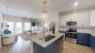 Located at 1800 Central Pine St in Montgomery, Texas, this single-story residence offers a thoughtfully designed open-concept layout that seamlessly connects the kitchen, dining, and living areas. The kitchen is a standout feature, showcasing two-tone cabinetry with bold navy lower cabinets and crisp white upper cabinets, granite countertops, stainless steel appliances, and a central island with an undermount sink and bar seating. A stylish pendant light anchors the space, adding a warm, decorative touch. Light wood-style flooring runs throughout the main living areas, contributing to a bright and airy atmosphere. The living room is generously proportioned, filled with natural light from large windows and French doors that open to an outdoor area. The bedroom is a comfortable retreat featuring plush carpeting, large windows that invite abundant natural light, and ample space for furnishings. The bathroom is well-appointed with granite countertops, white cabinetry, wood-style flooring, a combined tub and shower with tiled surrounds, and a vanity with a large mirror. Throughout the residence, a cohesive coastal-inspired color palette of navy, white, and warm neutrals ties each space together into a harmonious and inviting whole.