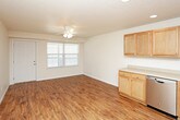 This single-floor home offers a practical and comfortable layout designed for easy everyday living. The open-concept living and dining area flows seamlessly into the kitchen, with warm hardwood-style flooring underfoot and a ceiling fan with integrated lighting overhead. Natural light filters in through a large window, brightening the shared space and creating a welcoming atmosphere.

The kitchen is well-appointed with warm-toned wood cabinetry offering generous storage, light laminate countertops, and a full suite of stainless steel appliances including a refrigerator, electric range, built-in microwave, and dishwasher. Recessed lighting and a textured ceiling add to the functional yet homey character of the space.

The bedrooms feature soft, neutral-toned carpet and ceiling fans, providing a comfortable and restful environment. Each room is finished with clean white walls, white baseboards, and ample space for furnishings. Multiple doorways suggest convenient access to closets and hallways.

The bathroom is clean and straightforward, featuring a tub-shower combination with chrome fixtures, a toilet, and a vanity with a countertop sink, all set against warm wood-style flooring. Throughout the home, the consistent use of neutral tones and practical finishes creates a cohesive, move-in-ready feel.