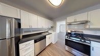 This single-floor residence offers a thoughtfully updated interior with a cohesive neutral color palette and durable finishes throughout. The kitchen is a functional highlight, featuring white shaker-style cabinetry, dark countertops, a tile backsplash, and stainless steel appliances including a gas range with overhead ventilation and a dishwasher. In-unit laundry is conveniently located within the kitchen area, adding practical value. The kitchen connects directly to additional living spaces via hardwood-style flooring that extends through the main areas.

The living and common areas are finished with wood-look flooring, crown molding, and large windows that allow generous natural light to filter in. The bedrooms are carpeted for comfort, each equipped with a ceiling fan and windows overlooking the exterior. The full bathroom includes a soaking tub and shower combination, a white vanity with chrome fixtures, wood-look flooring, and a window providing natural ventilation and light. The overall design maintains a clean, modern aesthetic with gray-toned walls, white trim, and a consistent style that ties the entire space together cohesively.