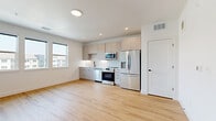 Located at 2735 Mountain Brook Dr in Longmont, CO, this thoughtfully designed one-bedroom, one-bathroom unit offers a clean, modern aesthetic across a single floor. The open-concept kitchen and living area serves as the heart of the space, featuring light wood-tone flooring that extends throughout and bright white walls that maximize the sense of openness. The kitchen is well-appointed with full-height cabinetry in a warm greige finish, a classic white subway tile backsplash, a full suite of stainless steel appliances including a French door refrigerator, electric range, over-the-range microwave, and dishwasher, and recessed ceiling lighting. A bank of large windows in the living area fills the space with natural light and offers views of the surrounding neighborhood. The bedroom is carpeted for comfort and features a ceiling fan, providing a quiet and cozy retreat. The bathroom showcases a contemporary design with a floating vanity in crisp white, generous drawer storage, a white quartz countertop, an undermount sink with matte black fixtures, and a large frameless mirror — all set atop light wood-look flooring. This unit presents a fresh, move-in-ready interior with cohesive modern finishes throughout.