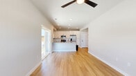 This two-story home in Fort Worth, Texas offers a thoughtfully designed layout spread across two floors. The main level centers around a bright, open-concept kitchen and living area finished with warm wood-look flooring throughout. The kitchen is well-appointed with white shaker cabinetry, a granite-topped island with an undermount sink, stainless steel appliances including a French door refrigerator and range, and a classic subway tile backsplash. Recessed lighting and a ceiling fan keep the space comfortable and well-lit. Sliding glass doors lead to a grassy outdoor area, filling the living space with natural light. A carpeted staircase leads to the upper level, where the spacious primary bedroom features plush carpet, multiple windows with blinds, and a ceiling fan. The en-suite primary bathroom showcases granite countertops, white cabinetry with matte black hardware, and a glass-enclosed shower. Four closets provide ample storage throughout the home. Additional rooms include a dedicated office, a laundry room, a utility room, and a hallway connecting the upper-floor spaces. With three full bathrooms, two bedrooms, and a clean, modern aesthetic, this home delivers functional comfort in a well-organized floor plan.