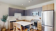 This single-floor, three-bedroom, two-bathroom residence offers a thoughtfully designed layout that balances functionality and modern aesthetics. The open kitchen is a standout feature, showcasing a two-tone cabinet design with slate-blue upper cabinets and natural light wood lower cabinets, complemented by a classic white subway tile backsplash and crisp quartz countertops. Stainless steel appliances, including a refrigerator, range, built-in microwave, and dishwasher, complete the space, while a central island with seating provides an ideal spot for casual dining. Light hardwood flooring flows throughout the unit, tying the spaces together cohesively. The living area is bright and welcoming, featuring recessed lighting and French doors that open to a private outdoor area, allowing natural light to flood in. Each bedroom is finished in neutral tones with ample natural light from wide windows fitted with blinds. The primary bedroom comfortably accommodates a full-size bed with room to spare. Both bathrooms are finished with light wood vanities, white quartz counters, and tub-shower combinations. The hallways are clean and bright, connecting each room efficiently, giving the home an organized, purposeful flow throughout.