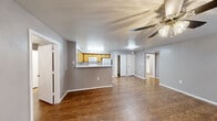 Located at 1088 Park Plaza in Austin, TX, this single-story home offers a practical and well-organized layout with two bedrooms and two full bathrooms. The open-concept living area is finished with warm wood-style flooring and neutral gray walls, creating a clean and inviting atmosphere. A ceiling fan with integrated lighting anchors the living space, adding both comfort and function.

The kitchen is positioned at the heart of the home, featuring honey-toned wood cabinetry, a speckled light countertop, and a peninsula that opens to the living area — ideal for casual dining or entertaining. White appliances, including a refrigerator, electric range, and over-the-range microwave, are included. An adjacent pantry closet provides additional storage.

The primary bedroom includes a ceiling fan, wood-style flooring, and direct access to a dedicated closet as well as a private bathroom. The second bedroom is equally well-appointed with similar finishes and its own closet. Both bathrooms feature white subway tile tub-shower combinations with chrome fixtures and a clean, functional design.

The entry area includes a closet for added convenience. Throughout the home, consistent flooring, neutral tones, and white trim create a cohesive and move-in-ready aesthetic suitable for a range of lifestyles.