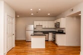 This single-floor space offers a thoughtfully designed layout centered around a well-equipped kitchen. The kitchen is a standout feature, showcasing white shaker-style cabinetry paired with dark countertops and a full suite of stainless steel appliances, including a refrigerator, range, microwave, and dishwasher. A central island with matching dark countertop provides additional workspace and serves as a natural focal point, while recessed lighting illuminates the area effectively. Warm-toned hardwood flooring extends throughout the unit, lending a cohesive and inviting character to every room.

The living areas are open and airy, benefiting from multiple windows fitted with horizontal blinds that allow natural light to filter through while maintaining privacy. Ceiling fans in the bedroom areas contribute to comfort and airflow. The rooms feature clean white walls and generous proportions, creating a versatile, move-in-ready environment.

The bathroom is finished with large-format dark tile flooring and includes a full tub-shower combination with brushed nickel fixtures, set against crisp white walls. Overall, the space presents a clean, modern aesthetic with practical finishes and a well-organized floor plan suited for comfortable everyday living.