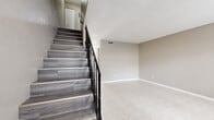 Located at 2130 S Palmetto Ave in South Daytona, FL, this two-story, 2-bedroom, 2-bathroom home offers a practical and well-organized layout spread across two floors. The main level features a bright living room with large tile flooring and a front-facing window that draws in natural light, alongside a functional kitchen outfitted with white cabinetry, dark marble-style countertops, tile flooring, and black appliances including a full-size refrigerator and electric range. A staircase with wood-look treads and a black iron railing connects the two levels, adding a clean visual element to the interior. The upper floor houses both bedrooms, each featuring light gray wood-look flooring, neutral walls, and textured ceilings. The generously sized primary bedroom includes a closet for storage. The second bedroom also offers a closet with louvered bifold doors and a window for natural light. Two bathrooms serve the home, one of which includes a single-sink vanity and a tub-shower combination with tile surround. Throughout the home, neutral tones and consistent finishes create a cohesive and functional living environment suited for comfortable everyday living in South Daytona.