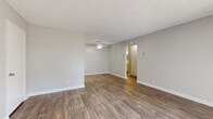 This single-floor residence offers a practical and well-organized layout, accommodating two bedrooms, three bathrooms, two kitchens, a living room, a hallway, and a closet. The living area is open and bright, featuring warm wood-style plank flooring, neutral beige walls, crisp white baseboards, and a textured ceiling with a ceiling fan — a combination that creates a clean, welcoming atmosphere. A sliding glass door dressed with vertical blinds allows natural light to filter in and provides access to the exterior. The kitchen is efficiently designed with white cabinetry, a marble-style countertop, a single-basin sink, and white appliances including a refrigerator and an electric range, all set against the same durable wood-style flooring. The bedrooms are comfortably sized, with the primary bedroom offering a built-in closet with sliding doors and a window dressed with vertical blinds that brings in outdoor light. The bathrooms feature white vanities topped with marble-style counters, mirrored medicine cabinets, and wood-style flooring, maintaining the cohesive aesthetic throughout. A bright hallway with open shelving connects the private areas of the home, completing a thoughtfully arranged floor plan.