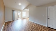 This renovated single-story unit offers two bedrooms and one bathroom across a well-designed, functional layout. The open living area features vaulted ceilings that enhance the sense of space, warm wood-style flooring throughout, and a bold accent wall that adds character. A sliding glass door provides access to an outdoor area and allows natural light to fill the room.

The galley-style kitchen is outfitted with white cabinetry, granite countertops, and stainless steel appliances, including an electric range, over-the-range microwave, and refrigerator. A window above the sink brings in additional natural light.

The bedrooms are carpeted and feature ceiling fans, offering a comfortable and quiet retreat. The bathroom is well-appointed with a dual-sink vanity topped with granite countertops, white cabinetry, wood-style flooring, and a full tub-shower combination with clean white tile surround.

A dedicated in-unit laundry area houses a full-size top-loading washer and dryer with overhead shelving. Throughout the unit, clean white trim and neutral tones contribute to a fresh, move-in-ready ambiance.