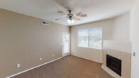 This single-floor residence offers a thoughtfully designed layout that balances comfort and functionality throughout. The living area is spacious and welcoming, finished with warm neutral-toned carpet and complemented by a ceiling fan with integrated lighting. Natural light flows in through large windows fitted with blinds, and a door provides direct access to the outdoors. A fireplace is positioned at one end of the room, adding a cozy focal point.

The kitchen is well-equipped and practical, featuring warm wood-toned cabinetry that extends to the ceiling for ample storage, granite-style countertops, and a suite of black appliances including an electric range, microwave, and refrigerator. Light tile flooring and a double-basin sink complete the space.

Adjacent to the kitchen, a dining or flex area showcases rich dark hardwood-style flooring and is connected to the rest of the home through a distinctive arched doorway, adding an elegant architectural detail. A pendant light and ceiling fixture provide layered illumination.

The bedroom is comfortably sized with plush carpet, a ceiling fan, and a bright window. The bathroom includes a full tub-shower combination with tile surround, granite-style vanity countertop, wood-toned cabinetry, and hardwood-style flooring, offering a clean and cohesive finish throughout.