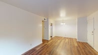 This single-story apartment at Park Lake Apartments offers a straightforward and functional layout unified by rich hardwood-style flooring that runs throughout the entire unit. The open living and dining area is anchored by an elegant chandelier and flows naturally toward a set of French doors that invite natural light and provide access to the outdoors. Adjacent to the dining space, a dedicated entry area leads to the kitchen and other rooms.

The kitchen is well-appointed with warm oak cabinetry offering ample upper and lower storage, dark laminate countertops, a double-basin sink, and white appliances including a range and refrigerator. A range hood above the stove and wood-look flooring complete the practical, organized space.

The bedrooms are comfortably sized, each featuring the same hardwood-style floors, neutral white walls, and windows fitted with blinds that allow for natural light and greenery views. One bedroom includes a closet with paneled doors and a ceiling vent for climate control. The overall ambiance of the unit is clean, neutral, and move-in ready, providing a versatile canvas for personalization.