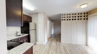 This single-level studio offers a thoughtfully designed open floor plan that maximizes every inch of available space. Light wood-look vinyl flooring runs throughout, lending a clean and cohesive aesthetic to the entire unit.

The kitchen is a standout feature, outfitted with rich dark-wood cabinetry, light granite countertops, stainless steel appliances including an electric range and refrigerator, an under-cabinet range hood, and a single-basin sink — providing a fully functional cooking space.

The main living area is defined by a distinctive architectural partition wall clad in large-format tile, topped with a row of glass block that allows natural light to filter through, adding a unique design element. A sliding glass door with vertical blinds opens to an outdoor area, bringing in additional natural light and providing outdoor access. A wall-mounted mini-split HVAC unit ensures year-round climate control.

A separate area with a window offers flexible use as a sleeping or living space, continuing the warm neutral color palette and wood-look flooring. The bathroom features a combined tub and shower, white tile surround, a bold navy accent wall, and matching wood-look flooring, completing this compact yet functional unit.