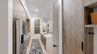 Located at 800 Van Cliburn Way in Fort Worth, TX, this thoughtfully designed 2-bedroom, 3-bathroom model residence showcases contemporary architecture and high-end finishes throughout its single-floor layout. Light wood flooring flows seamlessly across all living areas, complementing a clean, neutral palette.

The chef's kitchen is a standout feature, boasting flat-front wood cabinetry, a large white quartz waterfall island with seating, stainless steel appliances including a double wall oven and French door refrigerator, a sleek range hood, and globe pendant lighting with brushed gold accents. A black matte faucet adds a bold contrast to the crisp countertops.

The open living area benefits from floor-to-ceiling windows and sliding glass doors that invite abundant natural light and provide direct access to a private balcony. Both bedrooms also feature large windows with outdoor views and balcony access, creating a bright, airy atmosphere throughout.

The primary bathroom offers a frameless glass walk-in shower with large-format stone tile and a floating wood vanity, while the secondary bathroom features a soaking tub-shower combo with coordinating stone tile surround. Three full bathrooms ensure exceptional convenience for residents and guests alike. The overall ambiance is modern, refined, and effortlessly livable.