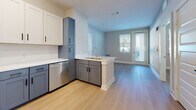 Located in Austin, TX, this well-designed 2-bedroom, 2-bathroom residence offers a thoughtfully arranged single-floor layout that maximizes comfort and functionality. The open-concept kitchen is a standout feature, showcasing a two-tone cabinetry design with crisp white upper cabinets and slate-blue lower cabinets, complemented by light quartz countertops, a white subway tile backsplash, and a full suite of stainless steel appliances including a range, built-in microwave, dishwasher, and refrigerator. A peninsula with a sink provides additional prep space and flows seamlessly into the living area, which is bathed in natural light from large windows and a glass-panel exterior door. Light wood-tone flooring runs throughout the home, lending warmth and continuity to each room. Both bedrooms are generously proportioned, featuring ceiling fans, multiple windows with views to the outdoors, and easy access to dedicated closets outfitted with wire shelving systems. The primary bedroom connects directly to its own bathroom and a walk-in closet. Both bathrooms feature tile flooring, blue-toned vanities with framed mirrors, and tub-shower combinations. Clean, neutral wall tones and modern black hardware finishes unify the home's contemporary aesthetic throughout.