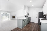 This single-floor residence offers a clean, bright, and thoughtfully designed layout across several well-defined living spaces. The open living area is finished with plush wall-to-wall carpeting and crisp white walls, creating a light and airy atmosphere. A sliding glass door with vertical blinds leads directly to a private balcony, allowing natural light to pour in while offering outdoor views of surrounding greenery. A wall sconce provides warm accent lighting, adding to the welcoming ambiance of the main living space.

The galley-style kitchen is a standout feature, showcasing white upper cabinetry paired with sage green lower cabinets, white quartz countertops, and warm wood-tone flooring. Stainless steel appliances — including a gas range, microwave, refrigerator, and dishwasher — complete this functional and stylish space.

The bedrooms continue the bright, neutral palette, with carpeted floors and windows fitted with horizontal blinds that invite natural light while maintaining privacy. The floor plan also reveals additional rooms, including what appears to be closet and utility spaces, contributing to strong overall storage.

The bathrooms are finished in a clean, minimal style. One features wood-look flooring and a tub-shower combination with chrome fixtures, while the second includes a white vanity with an undermount sink, patterned tile flooring, and a tub-shower unit — both designed for practicality and ease of maintenance.