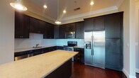 Located at 14-20 E Hubbard Ave in Columbus, OH, this well-appointed single-floor residence combines modern finishes with a thoughtful layout. Rich, dark hardwood flooring flows throughout the main living areas, complemented by crown molding that adds a refined architectural touch.

The gourmet kitchen is a standout feature, showcasing espresso-toned cabinetry with ample upper and lower storage, light granite countertops, a classic white subway tile backsplash, and a full suite of stainless steel appliances including a French door refrigerator, electric range, and built-in microwave. A generously sized island provides additional prep and gathering space, while pendant lighting overhead adds warmth and style.

The living area is open and airy, with recessed lighting and direct access to a private balcony, offering views of the surrounding neighborhood. Bedrooms feature plush carpeting and large windows that invite natural light. The primary bathroom includes a dual-sink vanity with stone countertops and a glass-enclosed shower, while a secondary bathroom offers a tiled tub-shower combination and dark vanity cabinetry. A dedicated laundry room with full-sized washer and dryer rounds out this well-equipped residence.