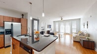 This thoughtfully designed single-floor residence offers a seamless open-concept layout connecting the kitchen, dining, and living areas. The kitchen is a standout feature, showcasing warm wood cabinetry, dark granite countertops, a full suite of stainless steel appliances, a marble-tiled backsplash, and a central island with bar seating — ideal for casual dining and entertaining. Pendant lighting adds a refined touch overhead, while hardwood flooring flows throughout the main living areas.

The living room is bright and inviting, featuring French doors flanked by large windows that flood the space with natural light and provide access to the outdoors. A ceiling fan adds to the room's comfort and functionality.

The bedrooms are carpeted and serene, each offering generous windows with blinds for light control and privacy. The primary bedroom includes a ceiling fan, ample wall space, and a calm, neutral palette. The bathroom features matching wood cabinetry, a dark granite vanity, tile flooring, and a glass-enclosed walk-in shower, maintaining the cohesive, modern aesthetic found throughout the home. Overall, the space delivers a clean, contemporary feel with warm, residential character.