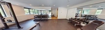 This contemporary space at 112 St James Street offers a versatile 2,010 square foot floor plan designed for multiple uses. The single-story layout boasts an open concept with seamless transitions between areas. Floor-to-ceiling windows flood the interior with natural light and provide lush outdoor views, creating a connection with nature.

The space features sleek hardwood flooring throughout, complemented by crisp white walls and recessed lighting. A stylish lounge area is furnished with modern seating, including blue bar stools and yellow accent chairs. Pendant lights with woven shades add a touch of warmth to the minimalist design.

A dedicated fitness area is equipped with exercise machines and free weights, visible through a large interior window. The space also includes a kitchenette or bar area, perfect for social gatherings or office refreshments.

Multiple entry points, including sliding glass doors, offer easy access to outdoor spaces, potentially a balcony or patio area. The flexible layout can accommodate various configurations, making it suitable for office use, fitness classes, or community events.

Security features such as smoke detectors and possibly keycard access are evident, ensuring safety and controlled entry. This multi-functional space combines aesthetics with practicality, offering a blank canvas for diverse professional and recreational activities.