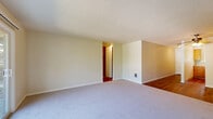 This single-floor residence offers a thoughtfully arranged layout comprising one bedroom, one bathroom, a kitchen, and a connecting hallway. The living area features a combination of rich hardwood flooring and plush carpet, neutral sage-green walls, a textured ceiling, and a ceiling fan. A full-width sliding glass door fills the space with natural light and provides views of surrounding greenery. The hallway, finished with hardwood flooring and textured walls, connects the main living area to the private rooms. The bedroom is a well-proportioned carpeted room with a window framing leafy outdoor views, a built-in closet with bi-fold doors, and access to the hallway. The kitchen is equipped with warm wood cabinetry, light countertops, a stainless steel sink, a white electric range, and a window that brings in natural light. The bathroom features large-format tile flooring, a wood-toned vanity with a white countertop and mirror cabinet, and a tiled shower-tub combo. Throughout the residence, neutral tones and consistent finishes create a cohesive and functional living environment.