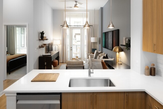 Kitchen and living area with oak cabinetry, white quartz countertops, and pendant lighting - Avalon Durham Apartments
