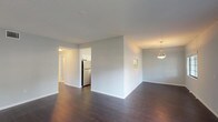 This single-floor residence offers a clean, modern aesthetic throughout, highlighted by a neutral gray-and-white color palette and consistent finishes across every room. The open-concept living and dining area features rich, dark hardwood-style flooring and multiple windows that invite natural light, creating a bright and welcoming atmosphere. A pendant light fixture adds a refined touch to the dining space.

The kitchen is well-equipped and thoughtfully designed, featuring white shaker-style cabinetry with ample upper and lower storage, white countertops, a stainless steel refrigerator, dishwasher, and range, as well as a central island that provides additional prep and counter space. A pass-through window connects the kitchen to an adjoining area, enhancing the open feel.

The bedrooms are finished with plush neutral carpeting, offer generous proportions, and include closets with bifold doors for convenient storage. Each room is served by consistent HVAC ventilation and shares the home's soft, understated color scheme.

The bathrooms are finished with striking marble-style tile flooring, dark-toned vanities with white countertops, large mirrors, and clean white fixtures, contributing to a polished and contemporary feel. Natural light filters into one bathroom through a gridded window, adding to the overall brightness of the space.