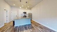 Located at 661 Wedgewood Ave in Nashville, TN, this thoughtfully designed one-bedroom, one-bathroom unit offers a well-organized layout across a single floor. The open-concept living and kitchen area is a standout feature, anchored by a large kitchen island with granite countertops and a built-in sink, illuminated by stylish pendant lighting. White shaker cabinetry lines the kitchen walls, complemented by a full suite of stainless steel appliances including a refrigerator, range, and microwave. Warm hardwood-style flooring flows throughout the main living areas, adding a modern yet inviting character to the space. The bedroom is generously proportioned, finished with soft carpeting, a ceiling fan, and a window that brings in natural light. It connects directly to a walk-in closet outfitted with multi-level wire shelving, providing ample storage. The bathroom continues the clean aesthetic with white cabinetry, granite-topped vanity, and matching hardwood-style flooring. Neutral tones and clean lines throughout create a bright, cohesive atmosphere well-suited for comfortable everyday living in Nashville.